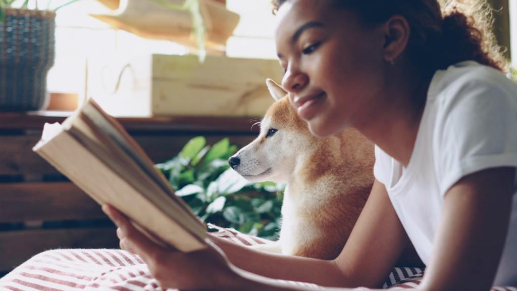 Young woman reads book with her dog companion.