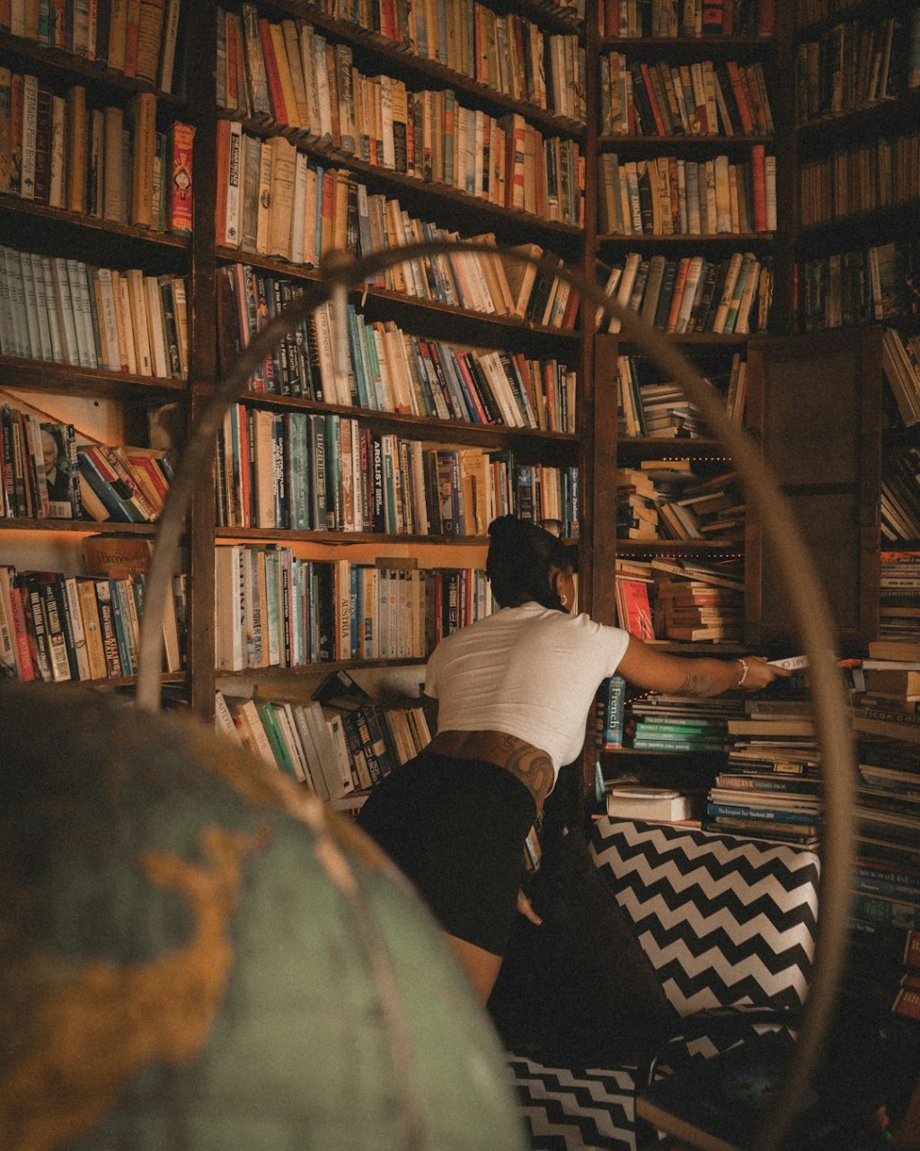 Person reaching for book on tall bookshelf